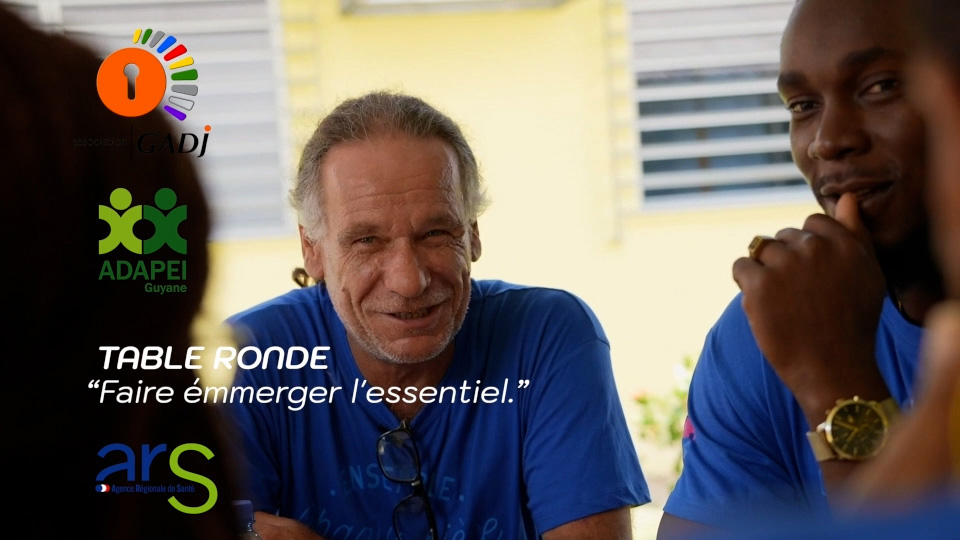 Table ronde ADAPEI Guyane 2026 — une formatrice échange avec un groupe de professionnels autour d'un classeur
